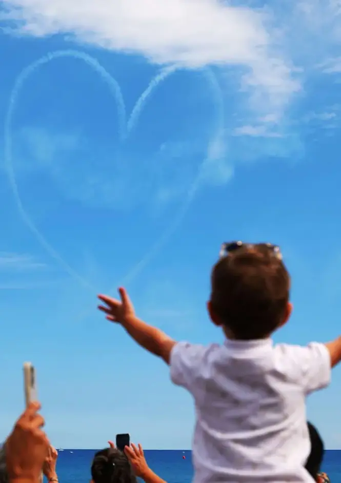 Un enfant observe une démonstration aérienne au-dessus de la mer